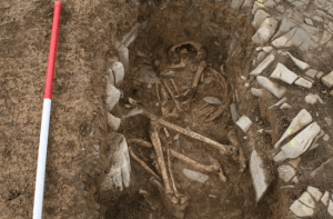 Een van de ineengekropen skeletten in een graf omlijnd met stenen