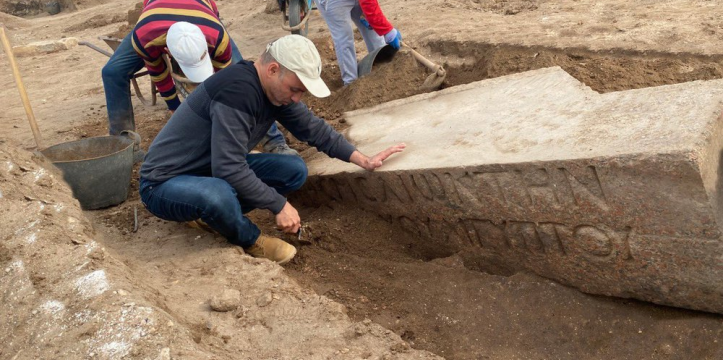 De archeologen graven een van de blokken met inscripties op