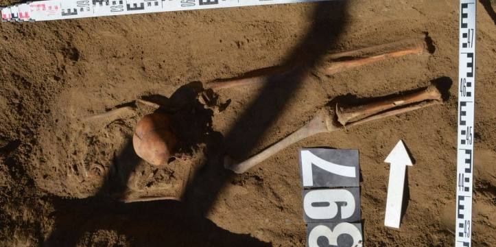 Opgegraven resten van een schedel tussen twee benen geplaatst