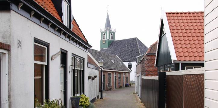 Straatje in Oudeschild met op de achtergrond het witte Zeemanskerkje. Straatje in Oudeschild met op de achtergrond het witte Zeemanskerkje.