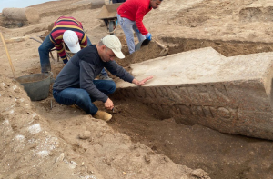 De archeologen graven een van de blokken met inscripties op